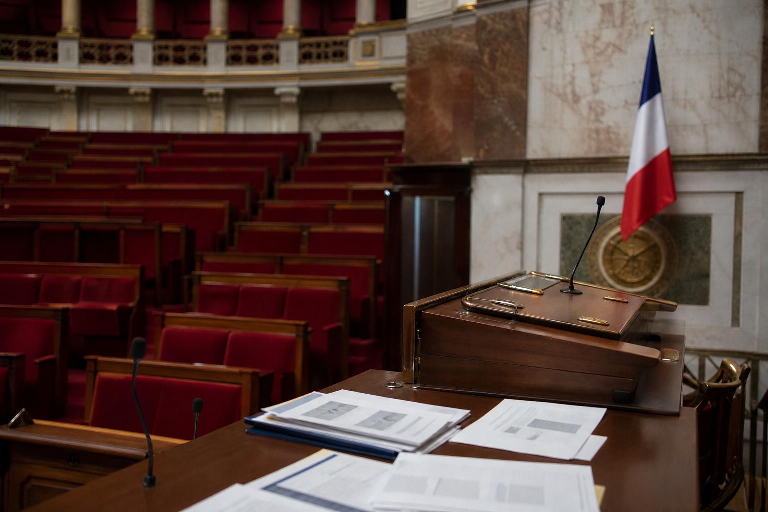 Salle de presse de l’Assemblée nationale avec pupitre vide, micros et sièges rouges pour illustrer une proposition de loi contre les violences dans la culture.