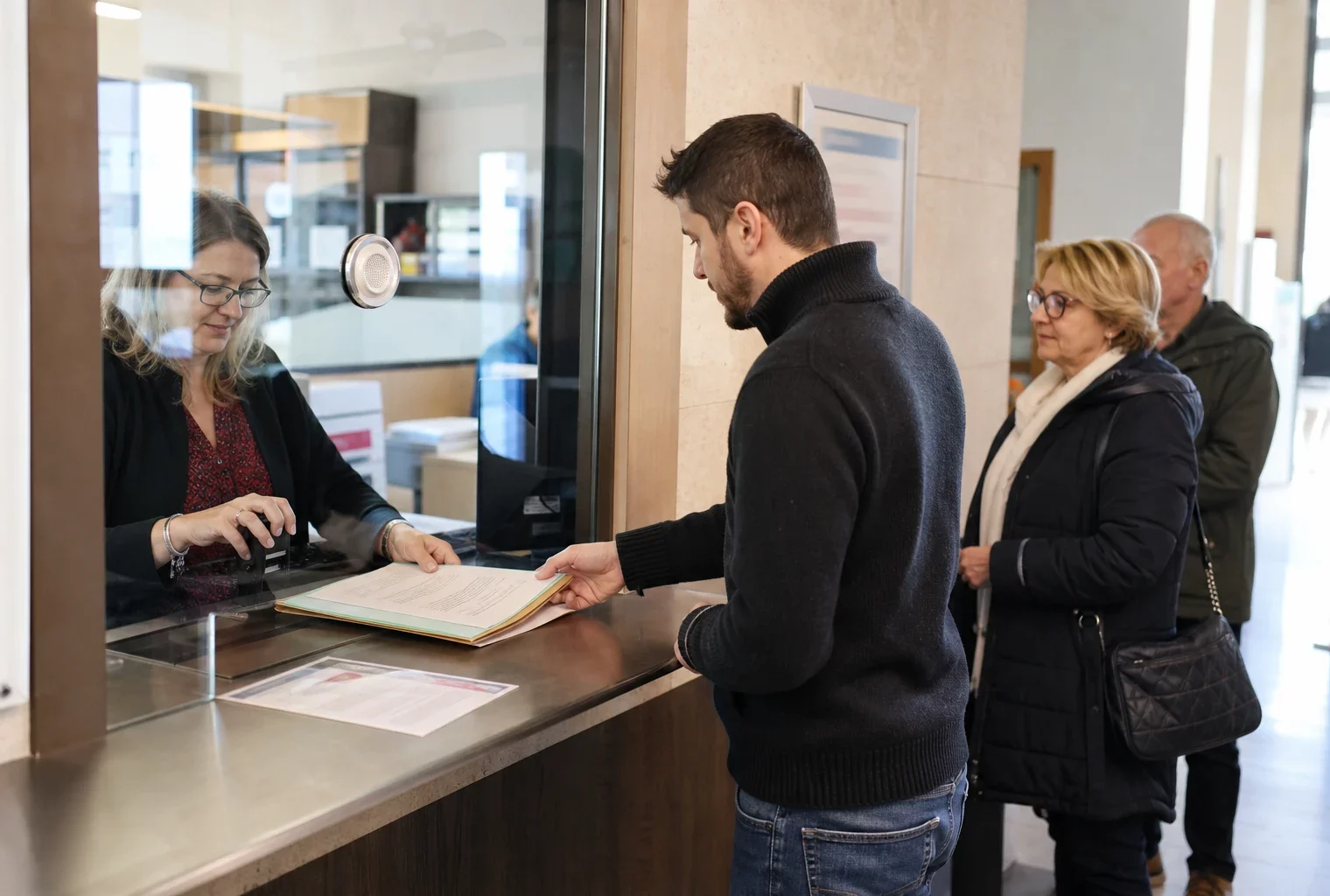 Accueil administratif lumineux dans une mairie, avec dossier posé au guichet et files de citoyens anonymes.