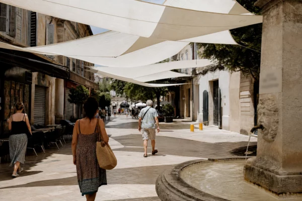 Rue française en été avec toiles d’ombrage, passants anonymes et façades ensoleillées pendant une vague de chaleur.
