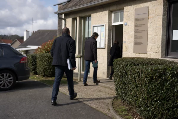 Scène calme devant un bâtiment public provincial français, avec des anonymes et une atmosphère de terrain liée à l’affaire Lyhanna