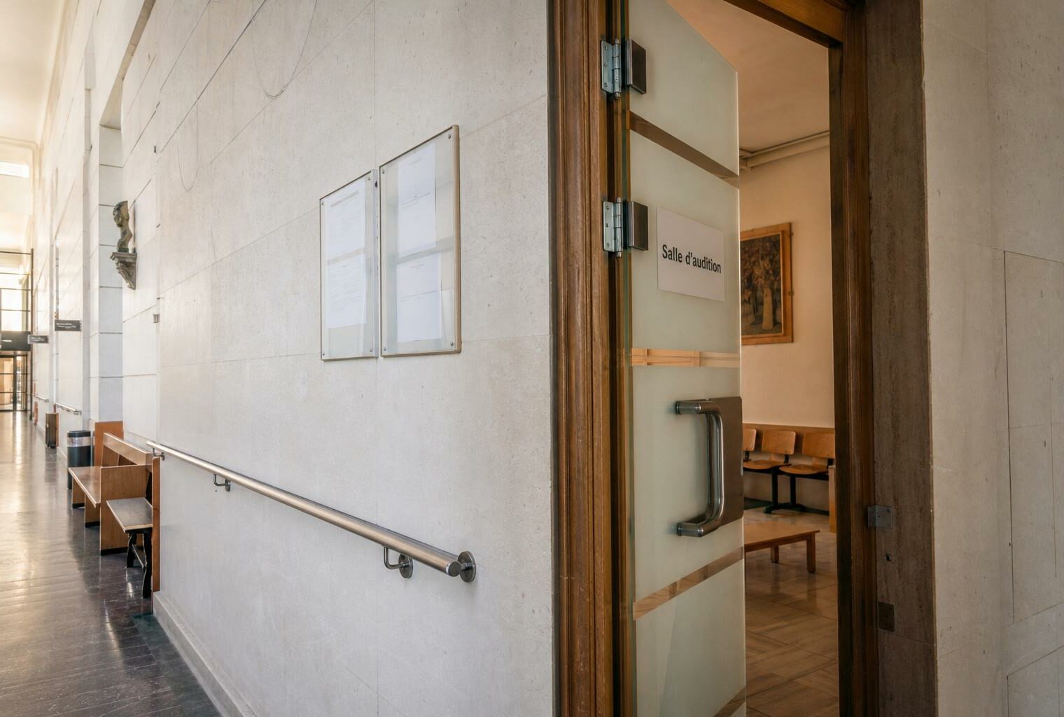 Couloir clair d’un bâtiment institutionnel français, porte d’audition entrouverte et ambiance administrative sobre.
