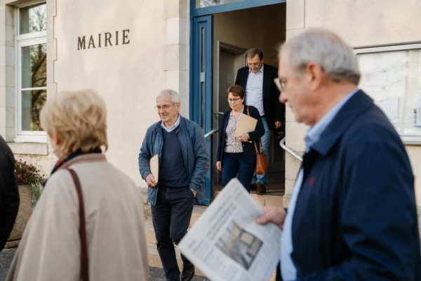 Des citoyens anonymes devant une mairie lors d’une réunion locale sur l’aide à mourir.