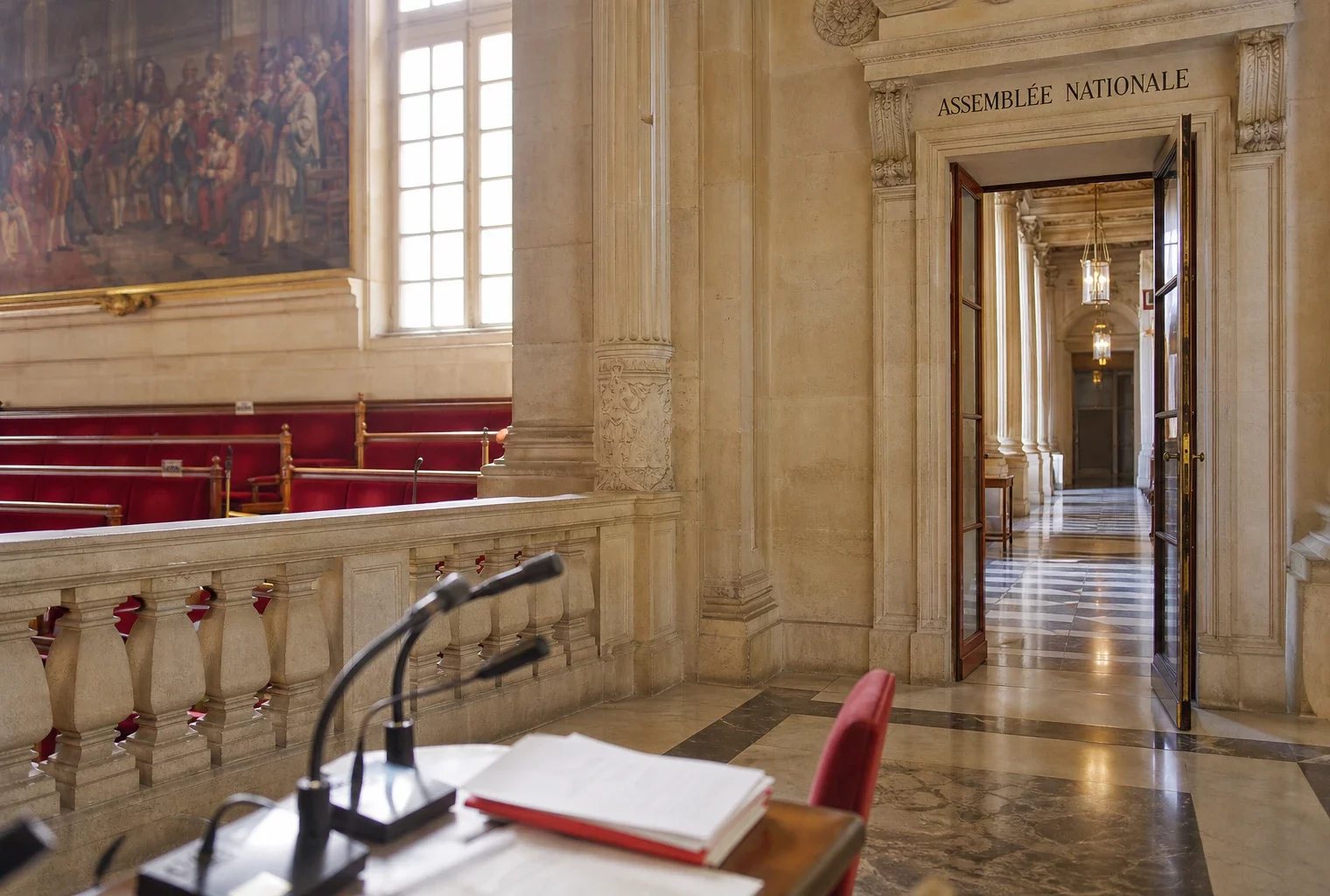 Couloir lumineux de l’Assemblée nationale avec microphones et marbre blanc, vue oblique et atmosphère institutionnelle.