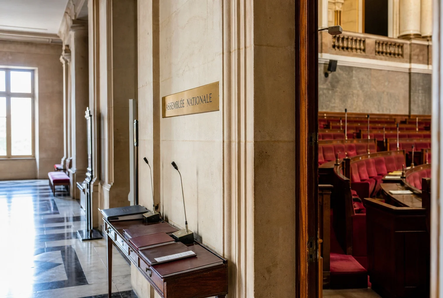 Couloir vide de l’Assemblée nationale avec dossiers et micros, dans une lumière naturelle claire.