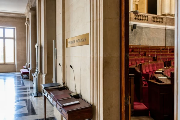 Couloir vide de l’Assemblée nationale avec dossiers et micros, dans une lumière naturelle claire.