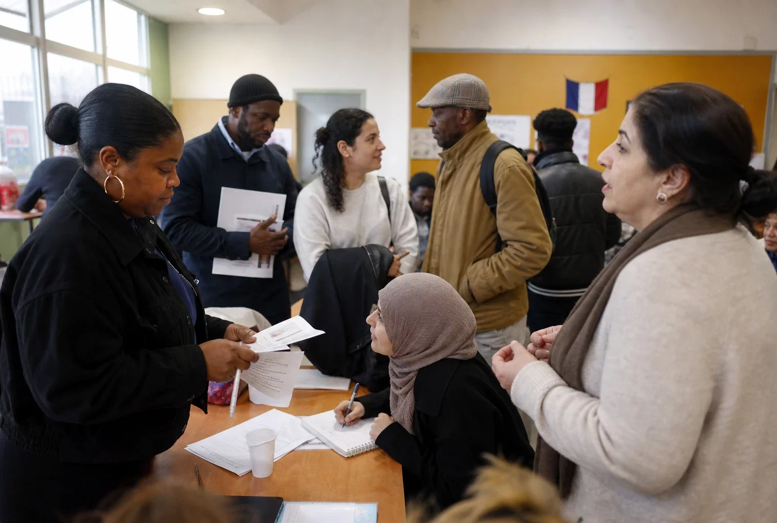 Salle d’association à Saint-Denis avec des habitants réunis autour d’un accueil local et de documents flous