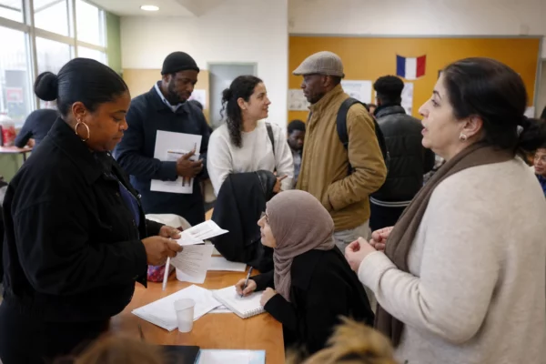 Salle d’association à Saint-Denis avec des habitants réunis autour d’un accueil local et de documents flous