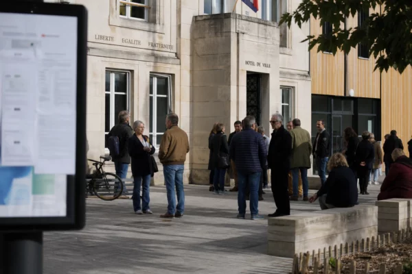 Scène de vie citoyenne à Aubervilliers devant une mairie, avec passants anonymes et ambiance politique locale.