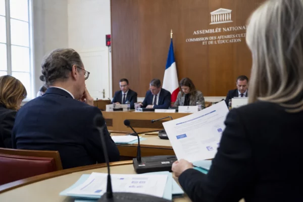 Audition parlementaire sur l’IA et le droit d’auteur, avec micros, dossiers flous et silhouettes anonymes dans une salle claire.