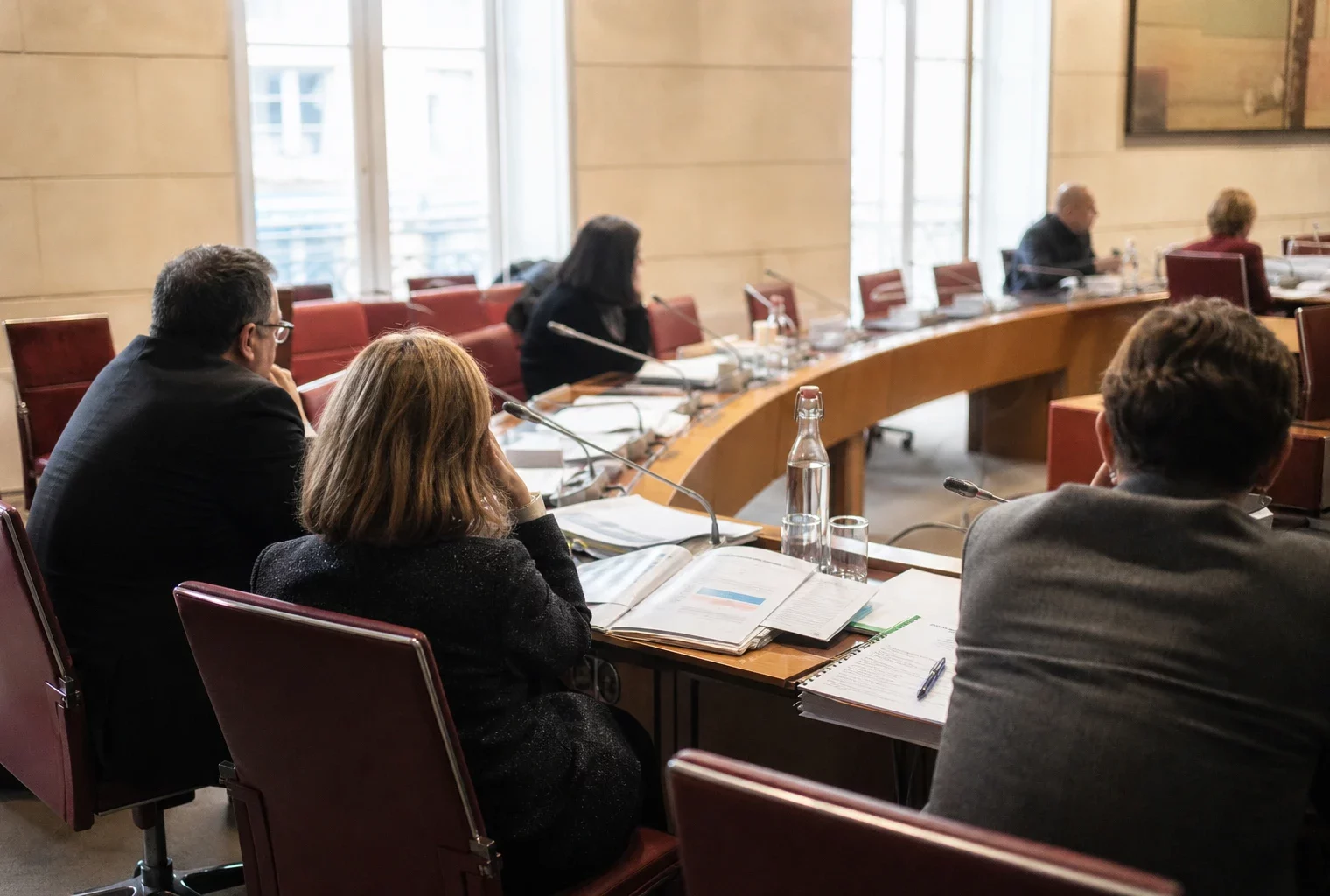 Audition parlementaire dans une salle claire du Sénat, avec micros, dossiers ouverts et silhouettes anonymes.