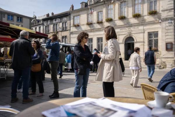 Reportage photo d’une place de ville française avec des habitants, un reporter et un climat politique local discret.