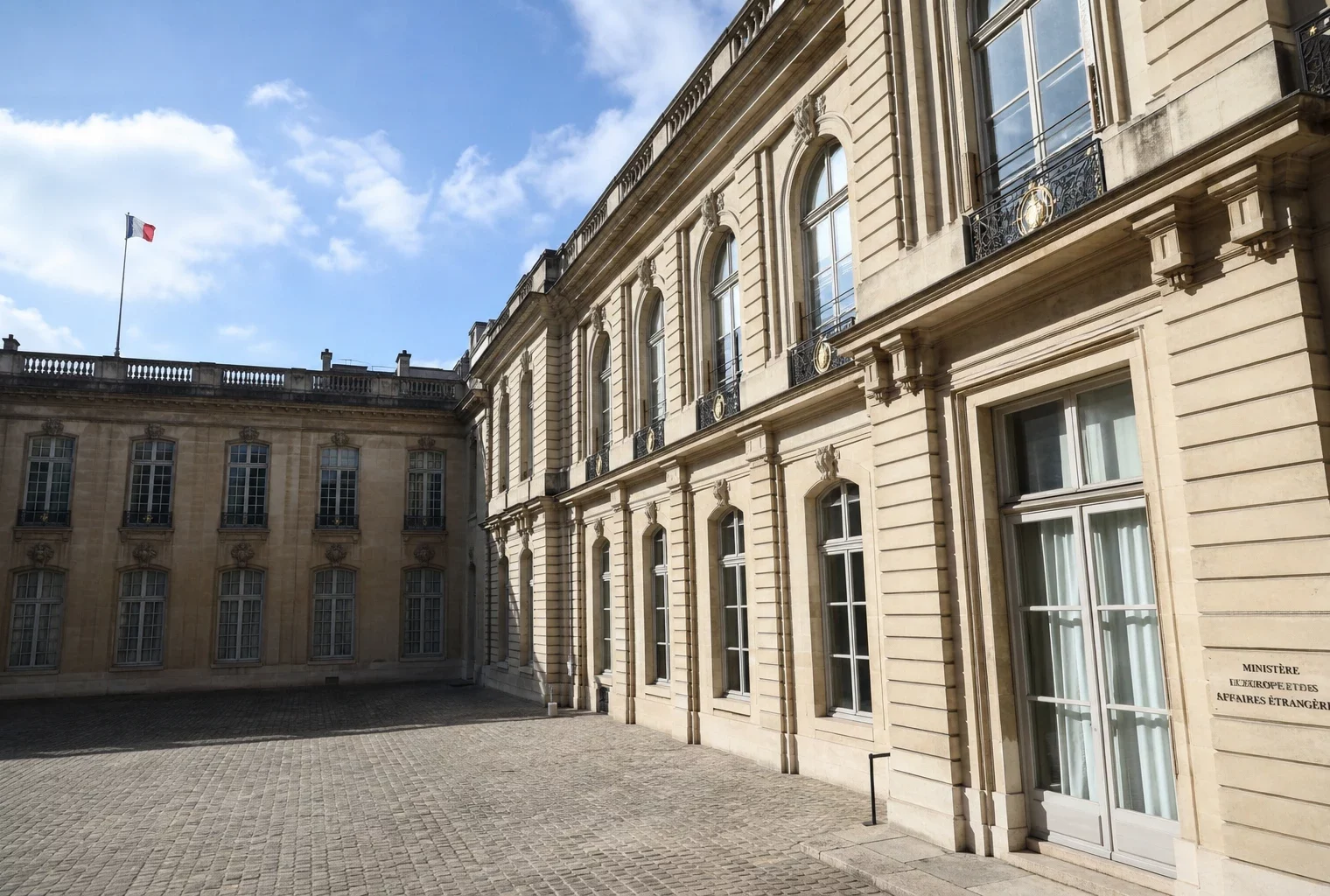 Cour vide du ministère français des Affaires étrangères à Paris, avec un petit drapeau tricolore au loin.