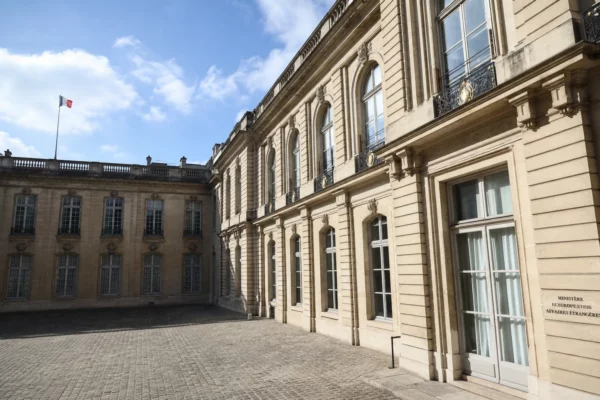 Cour vide du ministère français des Affaires étrangères à Paris, avec un petit drapeau tricolore au loin.
