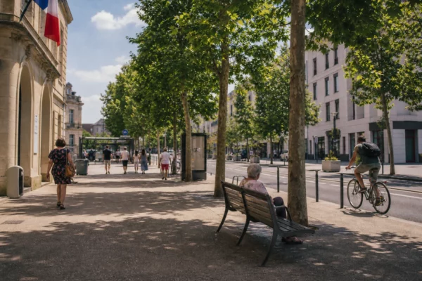 Rue française en été avec passants à l’ombre, chaleur visible et ambiance calme en Île-de-France.