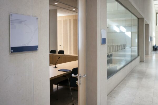 Couloir clair d’un régulateur français avec porte ouverte sur une salle d’audition vide