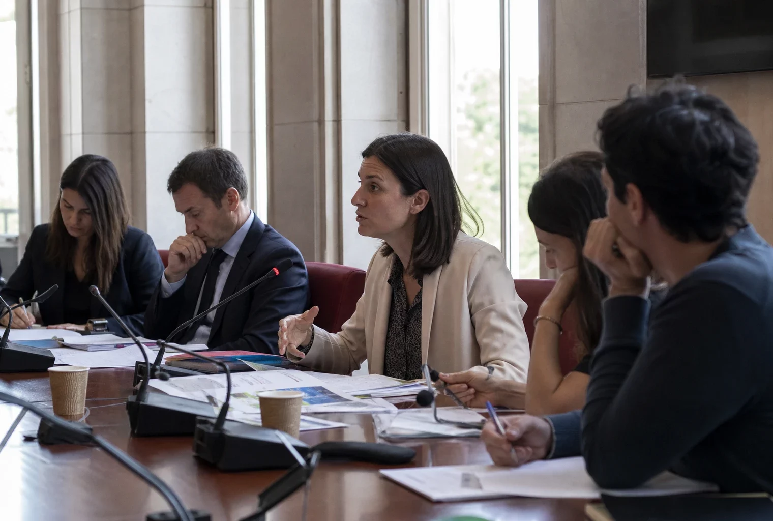Réunion de commission à l’Assemblée nationale avec cinq personnes, micros et dossiers sur une table.