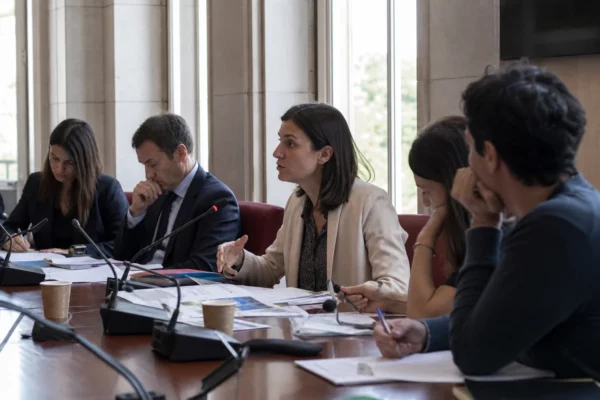 Réunion de commission à l’Assemblée nationale avec cinq personnes, micros et dossiers sur une table.