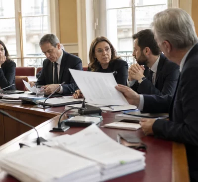Réunion parlementaire en commission avec députés anonymes, micros et dossiers autour d’une table