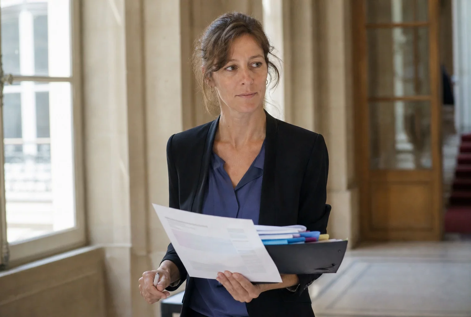 Portrait d’un haut fonctionnaire français dans un couloir ministériel lumineux, dossier à la main, ambiance estivale discrète.