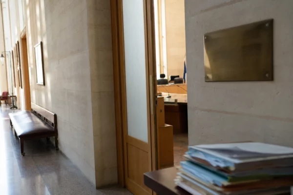 Couloir lumineux d’une institution française avec porte sobre et salle d’audition en arrière-plan.