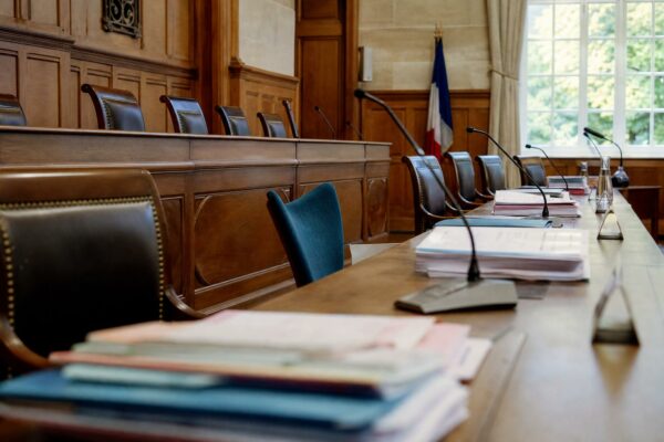 Salle du conseil municipal française avec chaise vide, micros et dossiers flous dans une lumière naturelle claire