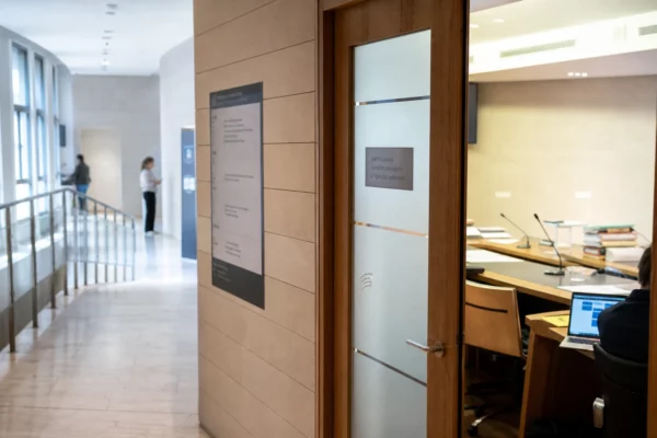 Couloir lumineux d’une institution française, avec salle d’audition et documents flous sur fond clair.