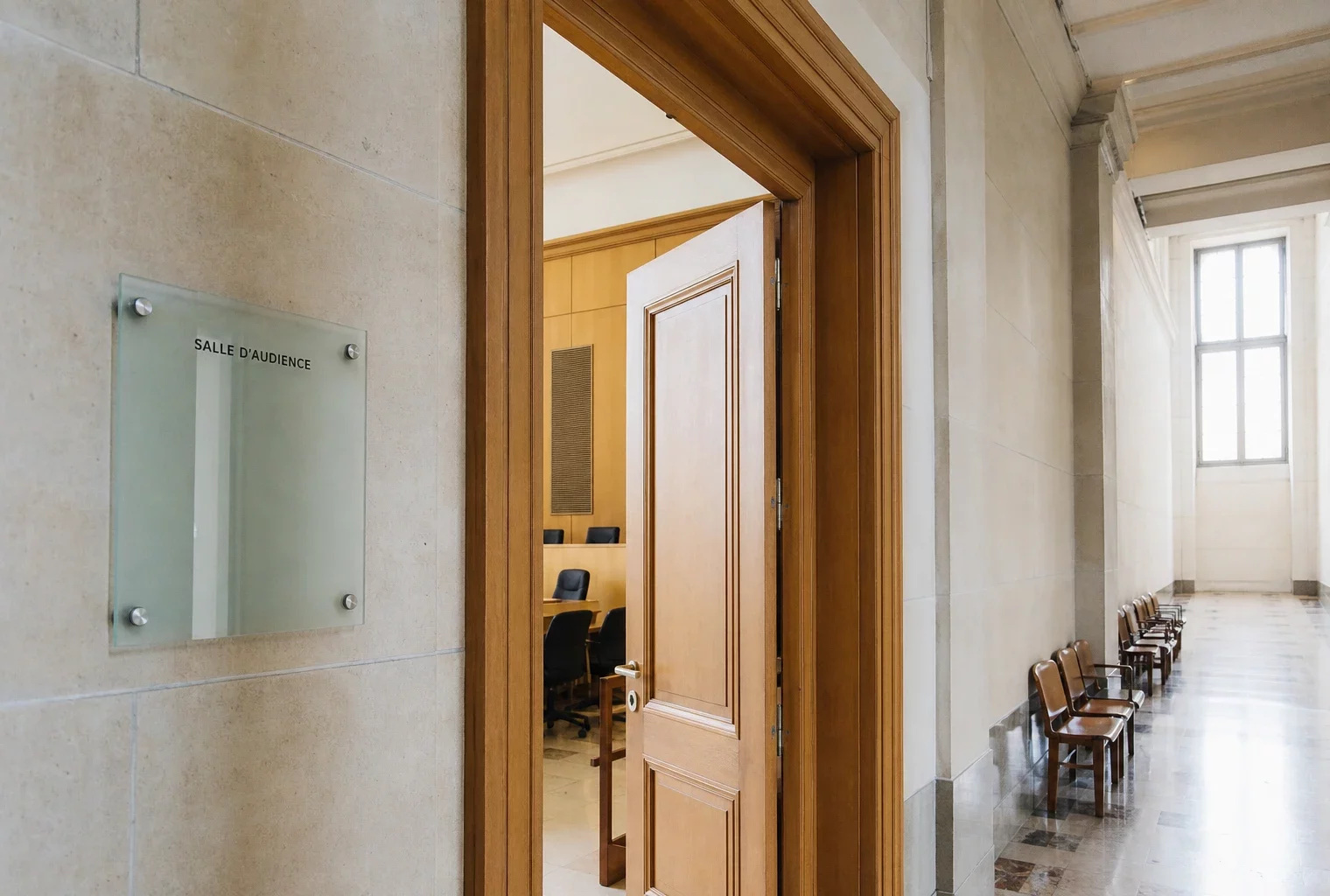 Couloir lumineux d’un bâtiment institutionnel français menant à une salle d’audition