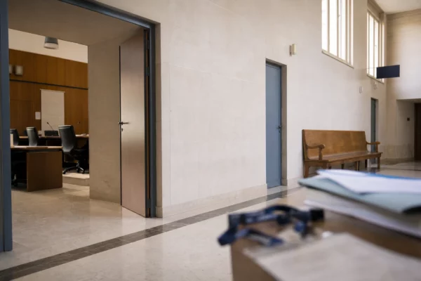 Couloir lumineux d’une institution publique française avec porte ouverte vers une salle d’audition