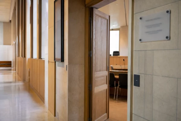 Couloir clair d’un bâtiment institutionnel français menant à une salle d’audition vide