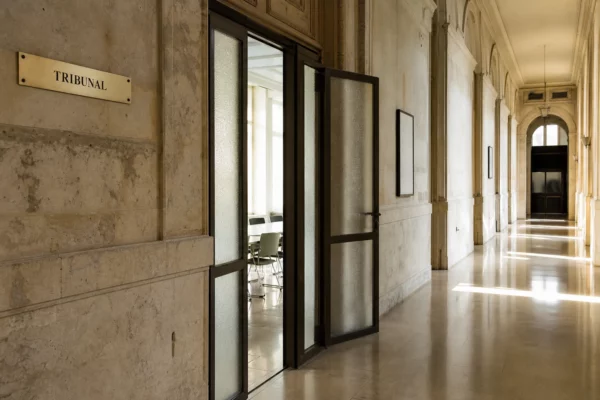 Couloir institutionnel européen lumineux et vide, photographié en angle oblique avec porte entrouverte et lumière naturelle.