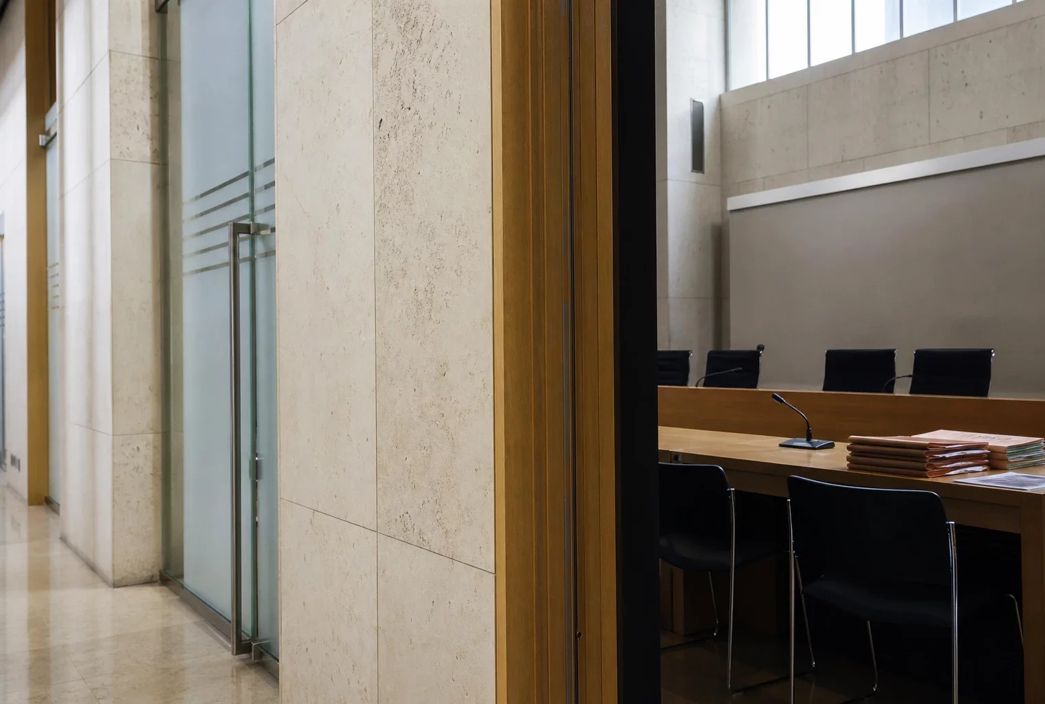Couloir clair d’une institution publique française avec salle d’audition visible et dossiers anonymes