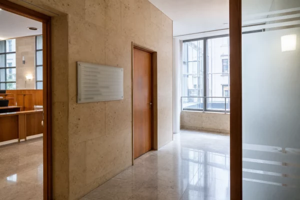 Couloir clair d’un bâtiment institutionnel français, avec porte sobre et lumière naturelle, en vue documentaire.