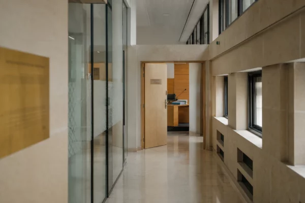 Couloir clair d’un bâtiment de justice avec porte entrouverte vers une salle d’audition