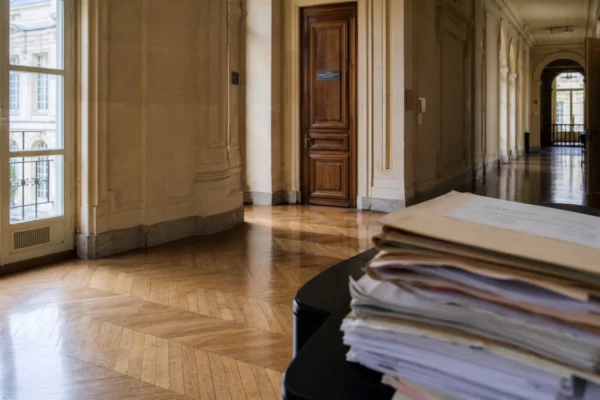 Couloir lumineux d’un bâtiment institutionnel parisien avec dossiers sur une table, ambiance sobre et officielle.