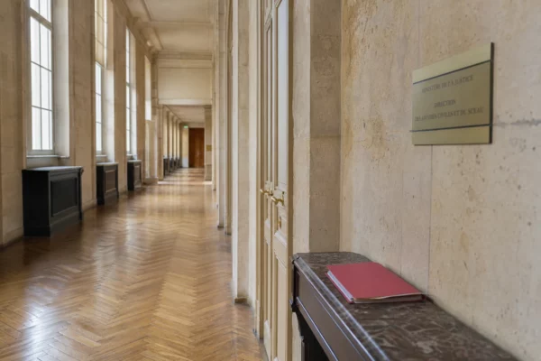 Couloir lumineux du ministère de la Justice avec dossier fermé, en référence à l’affaire Lyhanna