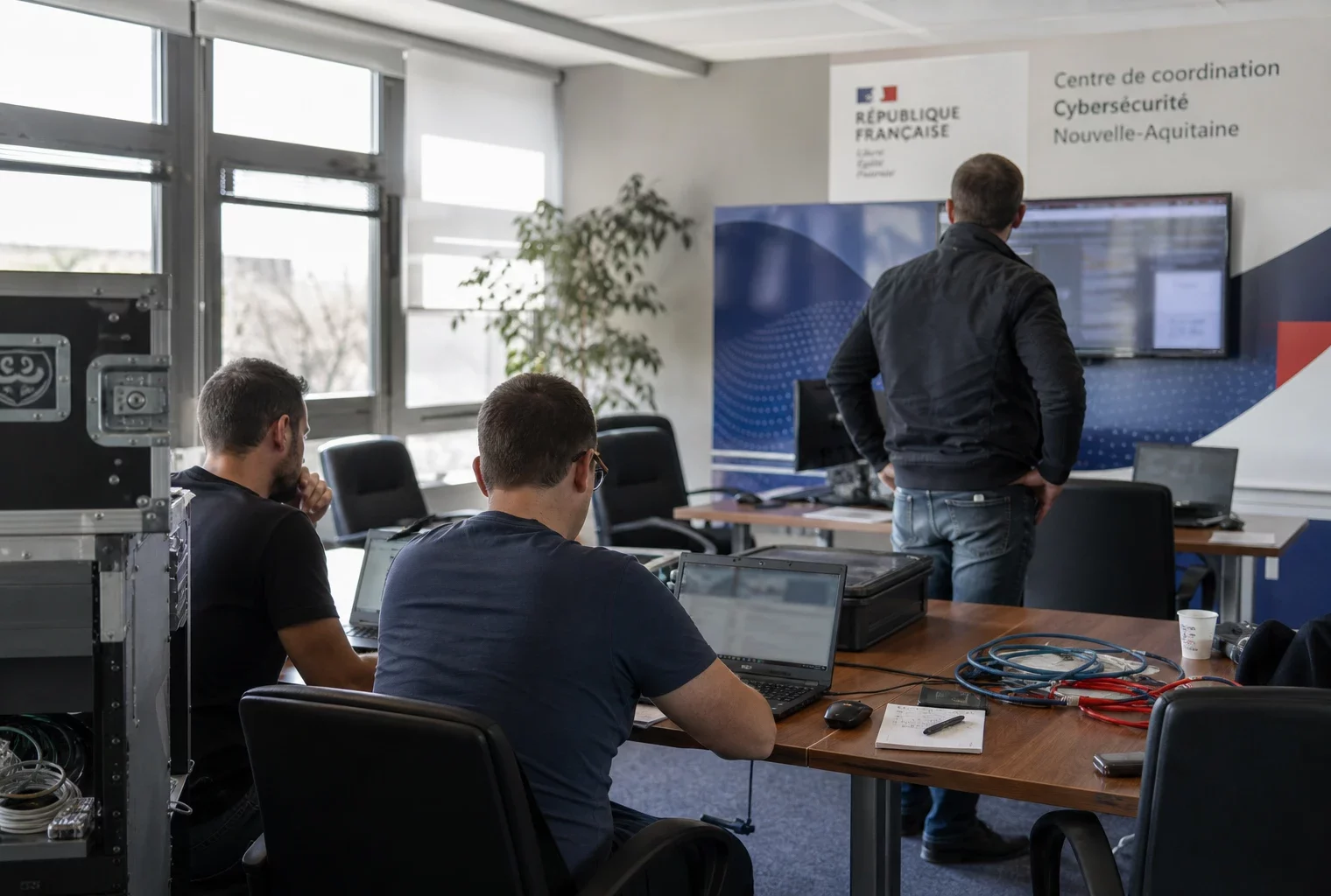 Salle de coordination cyber dans un bâtiment public français, avec techniciens anonymes et écrans flous en pleine activité.