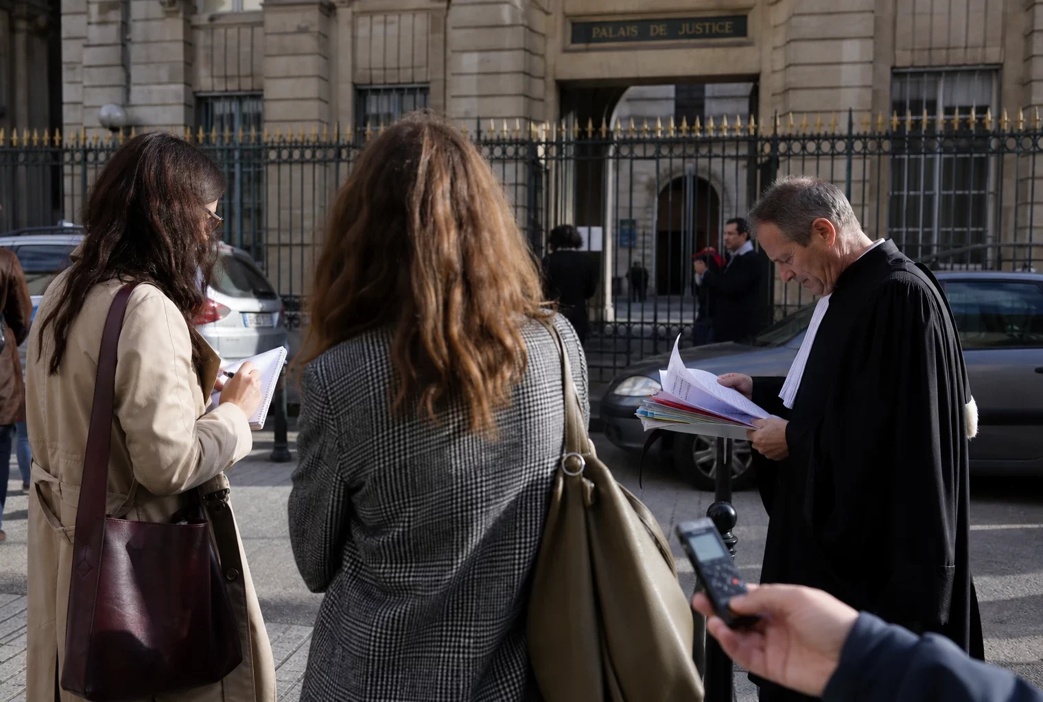 Des journalistes attendent devant un tribunal parisien, dans une scène calme liée à l’affaire de diffamation.