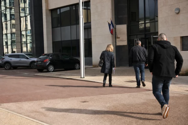 Scène calme devant un bâtiment administratif français, avec agents anonymes, voitures civiles et lumière du jour.