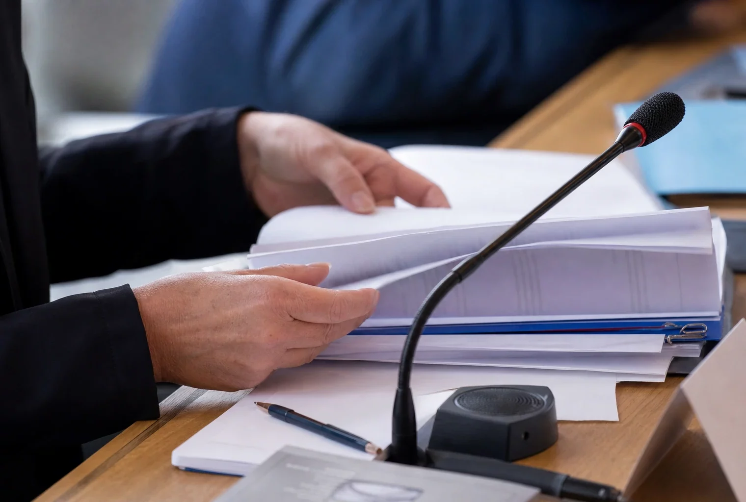 Mains anonymes consultant un dossier en commission avec micro de séance dans un cadre institutionnel français