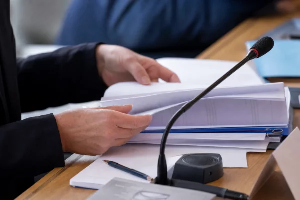Mains anonymes consultant un dossier en commission avec micro de séance dans un cadre institutionnel français