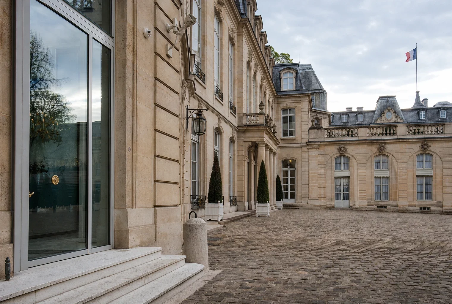 Cour intérieure de l’Élysée vide, en lumière naturelle, avec marbre clair et drapeau tricolore discret au loin