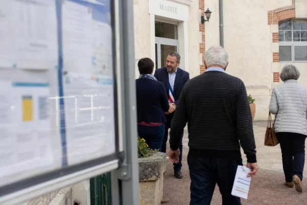 Des habitants et un élu local se croisent devant une mairie de quartier, dans une scène citoyenne lumineuse.