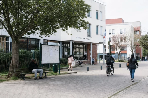 Devant la mairie de La Courneuve, des habitants anonymes traversent la place par temps clair