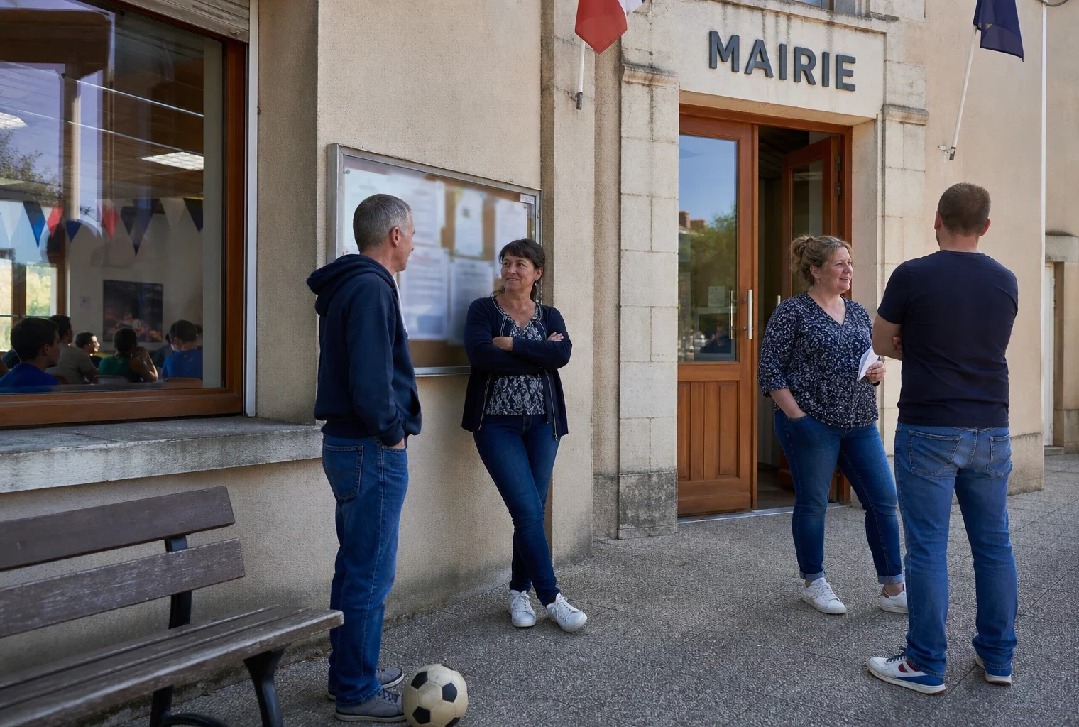 Des habitants discutent devant la mairie d’une petite commune française, dans une scène de vie locale liée au Mondial.