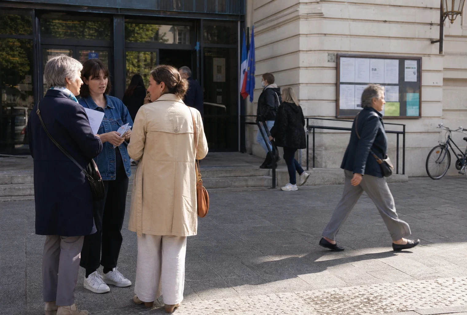Des passants et des agents municipaux devant une mairie parisienne après une soirée de tension