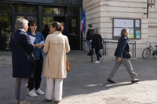 Des passants et des agents municipaux devant une mairie parisienne après une soirée de tension