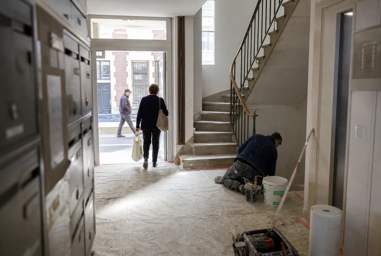 Cage d’escalier d’un immeuble résidentiel avec petits travaux de rénovation et habitants anonymes