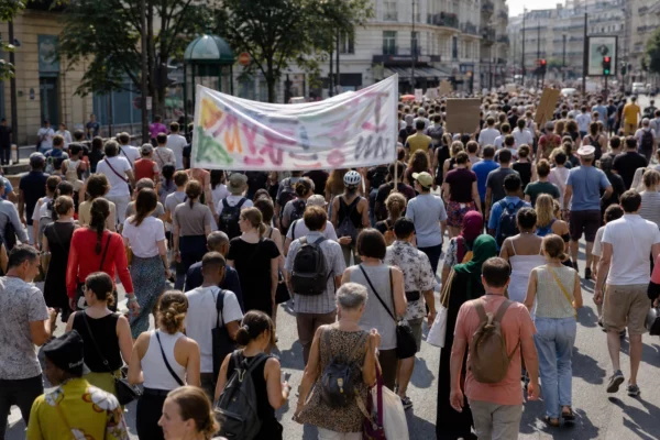 Marche antiraciste à Paris dans une rue ensoleillée, avec une foule de manifestants anonymes