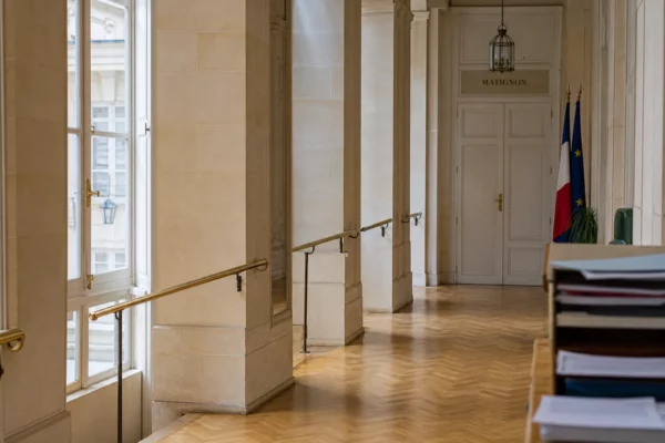 Couloir institutionnel vide à Matignon, lumière naturelle claire, ambiance sobre et officielle.