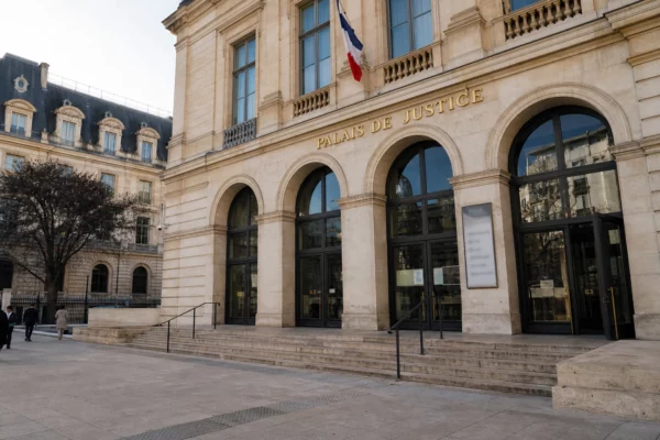 Façade du ministère de la Justice à Paris, vue oblique en lumière naturelle, avec quelques passants anonymes au premier plan.